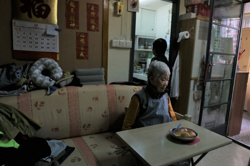 外傭兩年前離職，李小姐（後）擔當照顧媽媽杏金的責任。帶杏金婆婆去中心上課之餘，李小姐要製作早餐及替她洗澡。