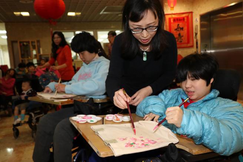 教养院教保老师萧月惠指导院生彩绘樱花在麻布袋上。