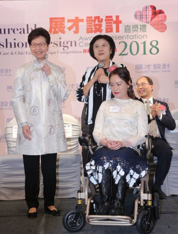 大會向特首林鄭月娥(左)致送名為「團結香港」的外套，該外套乃由使用輪椅的展才設計師吳貴玲女士(前排右一)特意為特首設計