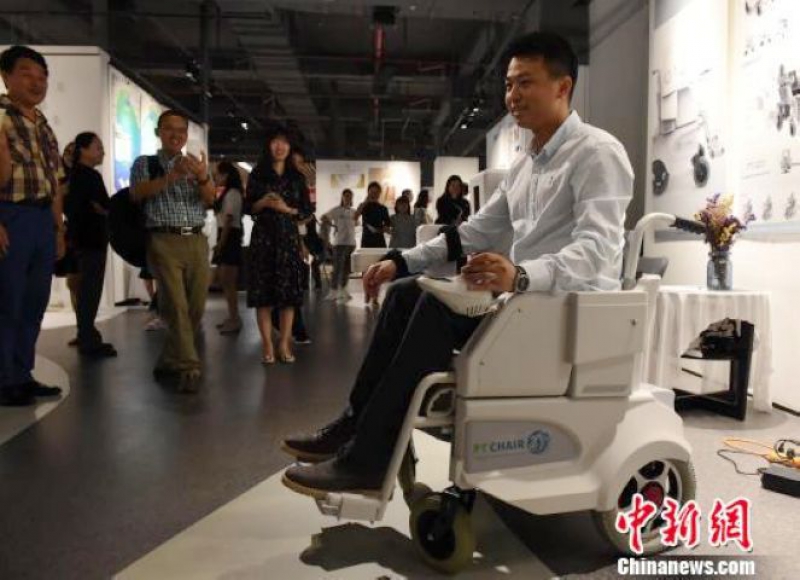 圖為新型輪椅設計者坐在輪椅上介紹其功能