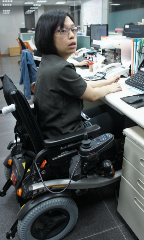 因小腦出血留有運動失調後遺症的小瑄，在勞工局協助提供電動輪椅排除職場障礙後，她樂在工作