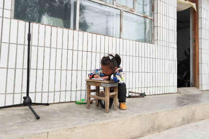 記者採訪時，田佳一個人在小板凳上寫作業