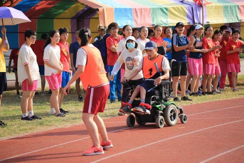 台南永仁高中三年级陈俊仲人生第一次参加大队接力，在轮椅完成第一棒任务（右）接棒给同学。
