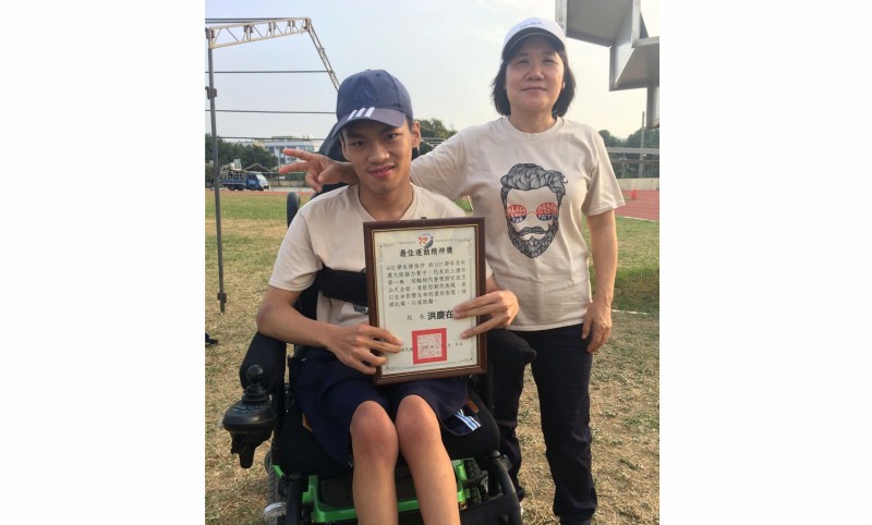 台南永仁高中三年級陳俊仲（左）用輪椅完成人生第一次參加大隊接力，校長洪慶在頒給他最佳運動精神獎