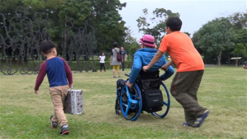 若是路不平，总会有人协助张世明推轮椅，小朋友也非常乐意帮忙