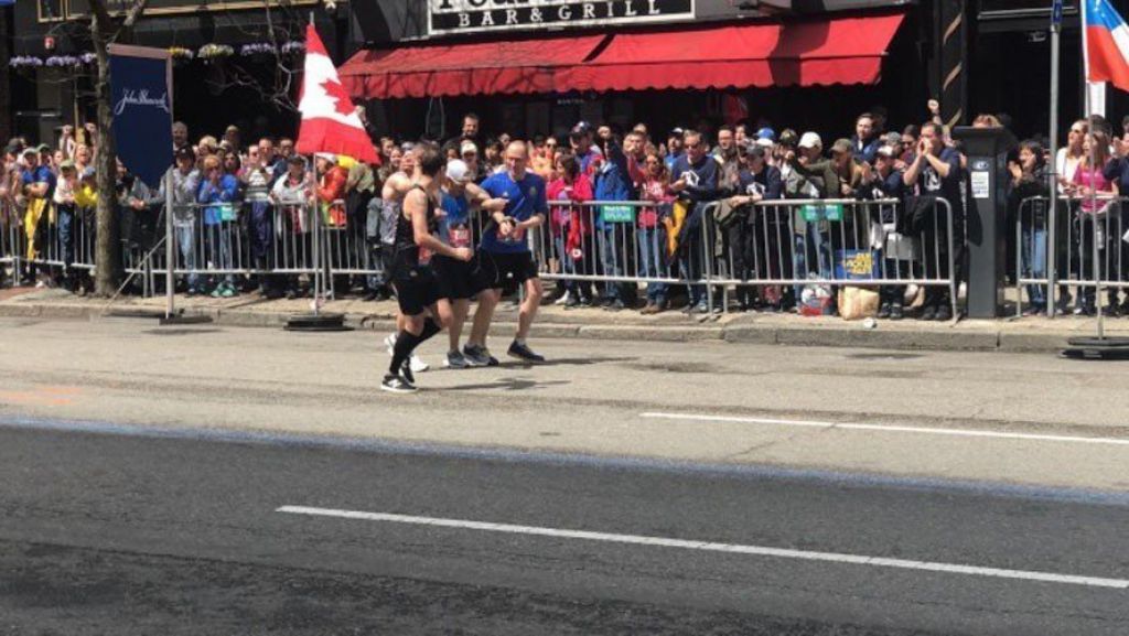 有一位跑者在快到終點線前支撐不住了，馬上兩位馬拉松跑者停下來摻著他走向終點