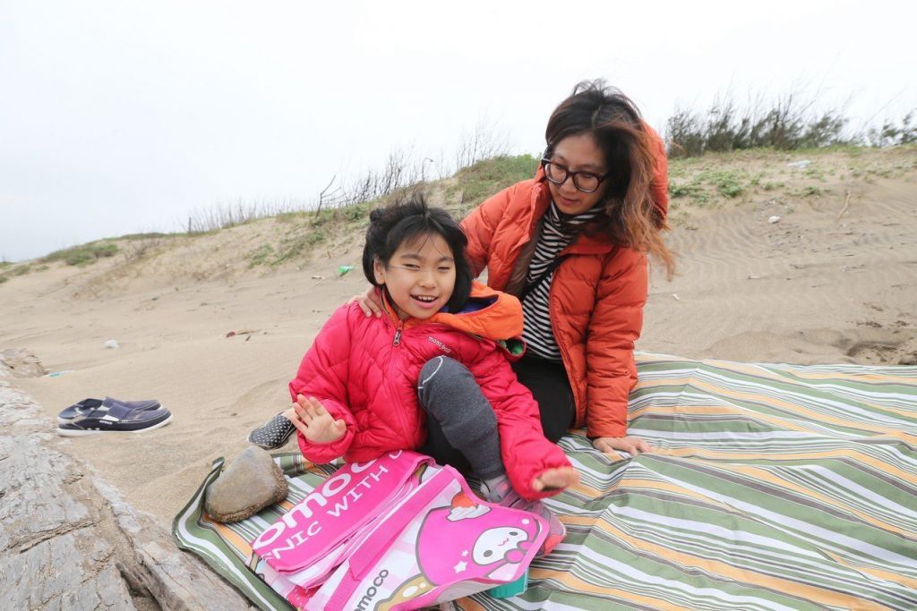 黃澄寗（左）與母親鄭淑娟看海，海風吹拂在澄寗的臉上，她展露笑容
