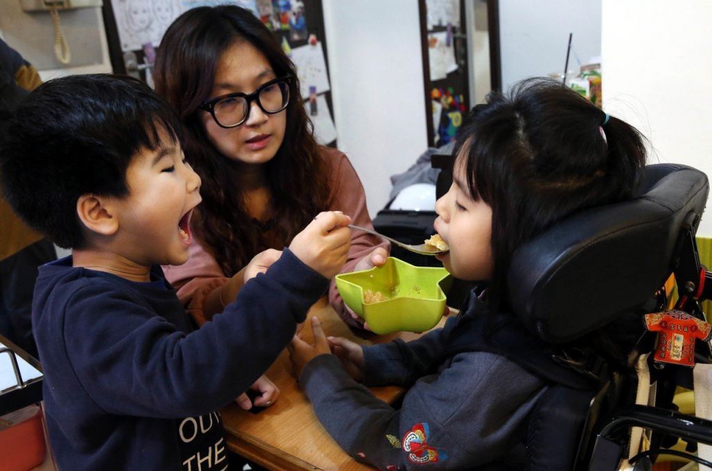 弟弟黃睦恆（左）看見父母照顧姐姐澄寗，也學著餵姐姐吃飯