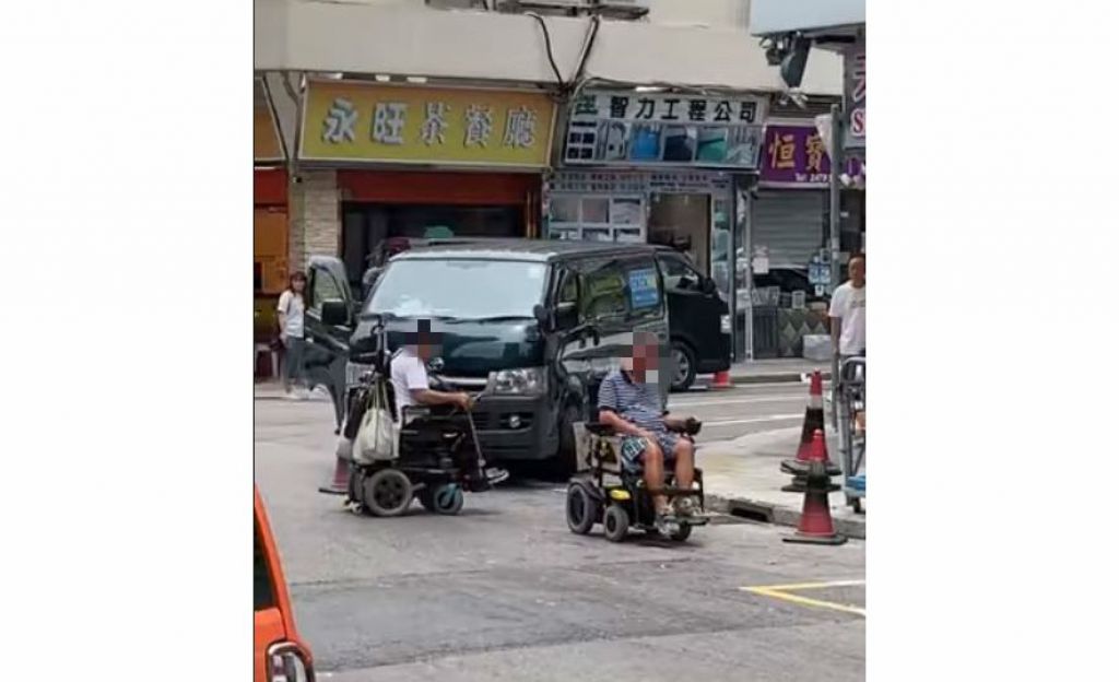 兩名需靠電動輪椅移動的傷殘人士無奈地在路邊來回移動