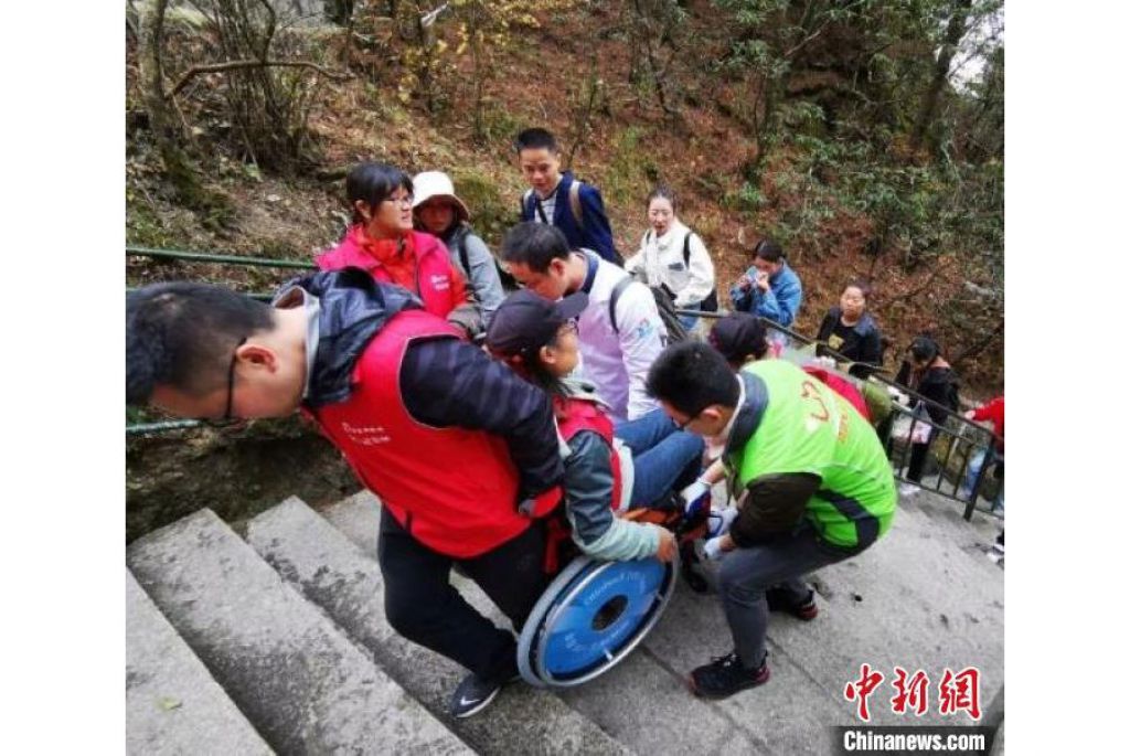 “轮友”在志愿者的帮助下登山