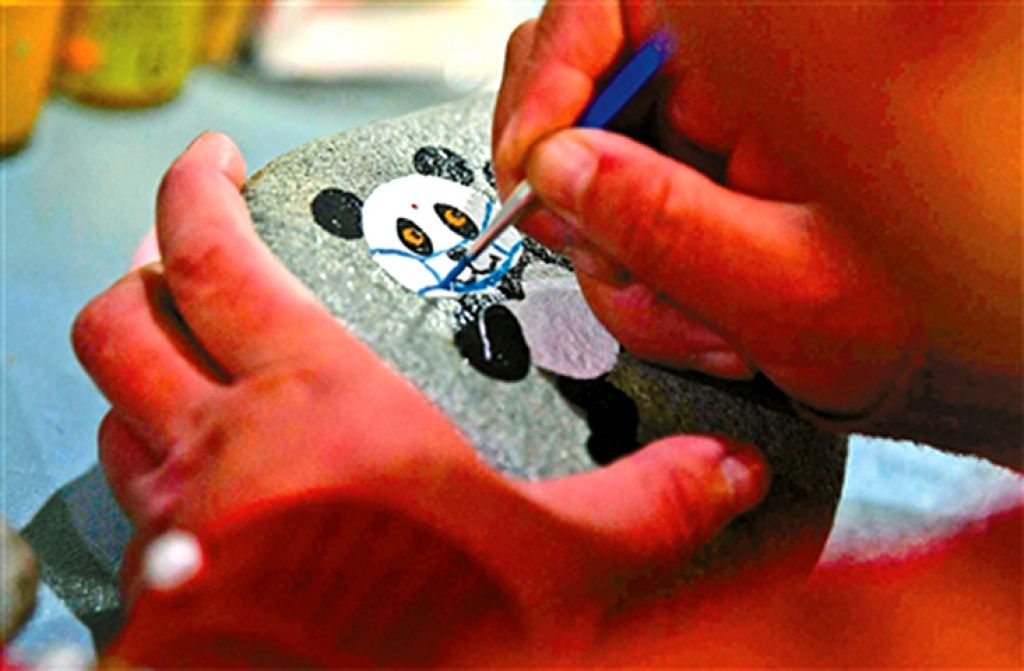 刘伟超在新绘制的“国宝石”上为熊猫画上口罩