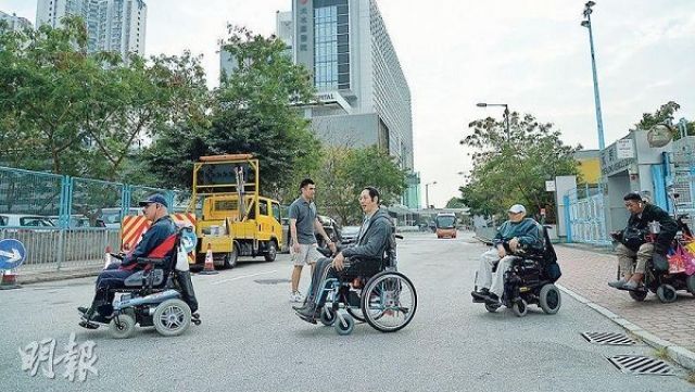 自强协会属下四轮社区联会的成员庄先生(左起)、黄炳伸、阿本及庆文上周试行从颂富站到天水围医院(图中)的路段,从天瑞路转入天坛街需过马路,其间需闪避左右驶来以及于露天停车场出入的车辆。