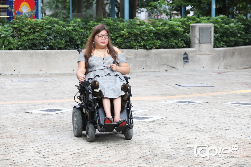 Carmen的腰腳乏力，因此坐輪椅時要在大腿旁放上兩隻公仔，讓大腿倚靠著以固定位置。