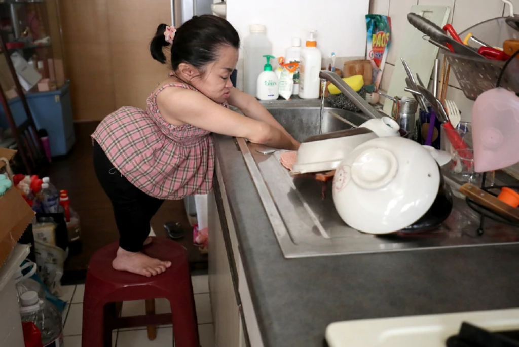 陳靜琪必須踩在塑膠椅上才搆得到洗碗槽，她因為罹患成骨不全症導致身材特別嬌小。康仲誠攝