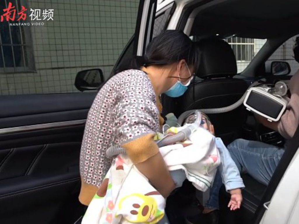 媽媽小心翼翼抱兒子上車準備回家。