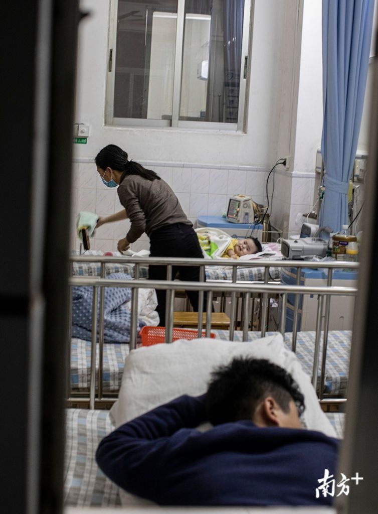 疲倦的丈夫趴在一旁小休，杜佳為兒子護理。