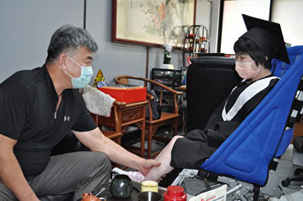 副校長陳寶億心疼周昀錡以輪椅代步，每次碰面總會輕輕幫她按摩血液循環不良小腿。