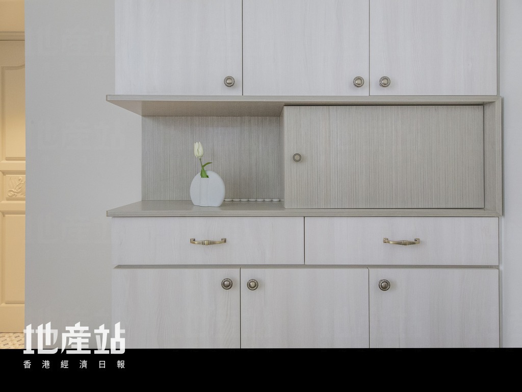 梳化側的全高櫃，劃一以灰色木皮及白色木紋生態板襯托青銅手抽。同時加入中空飾架，方便擺放鎖匙及盆栽。