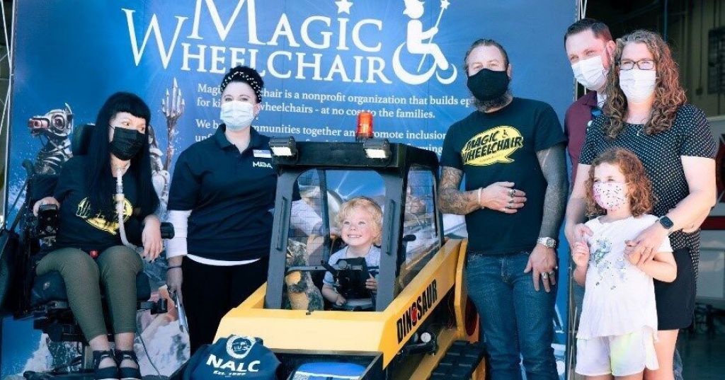 （從左到右）Christine Getman，魔術輪椅；Jenny McGahan，肌肉萎縮症協會；MDA 家族成員梅森穿著他的新“恐龍”前裝載機輪椅服裝；Scottie Foertmeyer，魔術輪